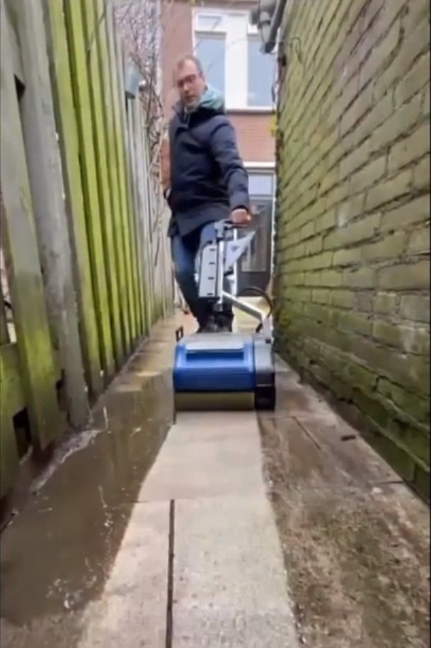 A contractor is cleaning wet concrete floor using commercial floor scrubber